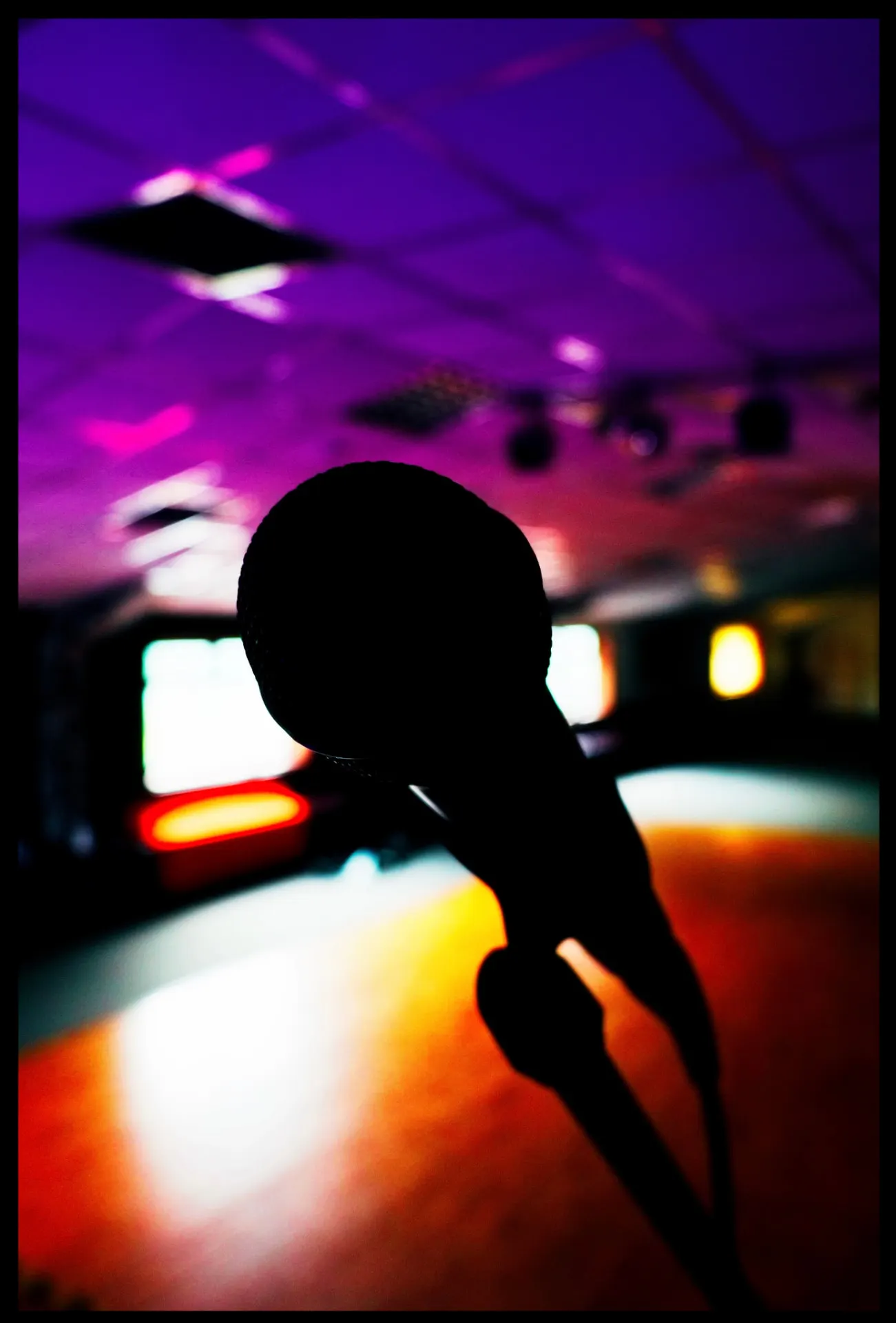 A microphone on stage under purple and orange stage lighting at New Imp Studio